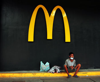 Full length of boy sitting on yellow wall