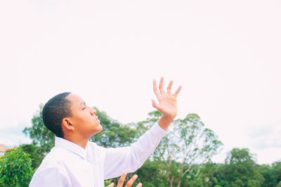 Low angle view of young woman against clear sky