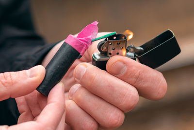 Close-up of man igniting firecracker outdoors