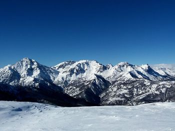 Scenic view of snowcapped mountains against clear blue sky