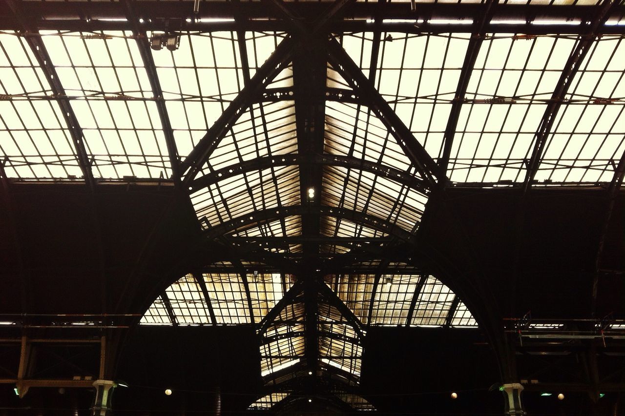 indoors, ceiling, low angle view, built structure, architecture, glass - material, skylight, window, interior, transparent, silhouette, metal, pattern, architectural feature, modern, no people, illuminated, building, grid, sky