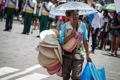 Senior woman with umbrella selling bags in market