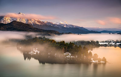 Scenic view of lake by mountains against sky during sunset