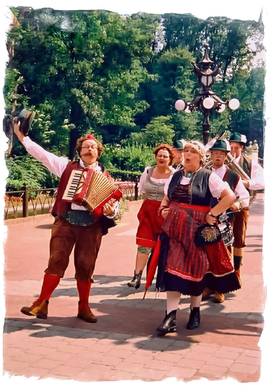 real people, full length, outdoors, cultures, smiling, dancing, happiness, celebration, day, tradition, leisure activity, standing, togetherness, tree, lifestyles, performance, young adult, young women, men, musical instrument, people