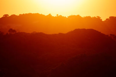 Scenic view of silhouette mountains against orange sky