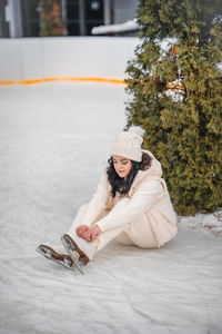 Rear view of woman sitting on snow