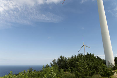 Low angle view of wind turbines against sky