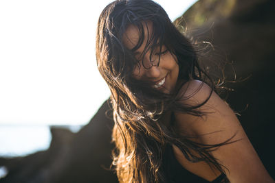 Young latina woman laughing by the ocean at golden hour in summertime