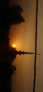 Silhouette of electricity pylon against sky during sunset