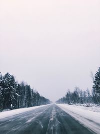 Road amidst trees against sky during winter