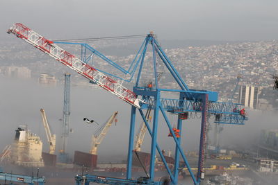 Cranes at commercial dock against sky