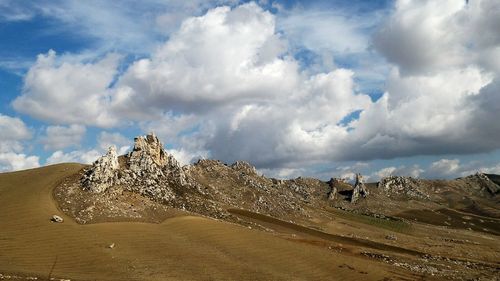 View of barren landscape against cloudy sky