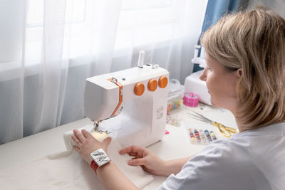 Woman using sewing machine at home