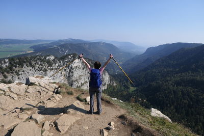 Rear view of friends standing on mountain against sky