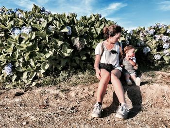 Full length of couple sitting on field against sky