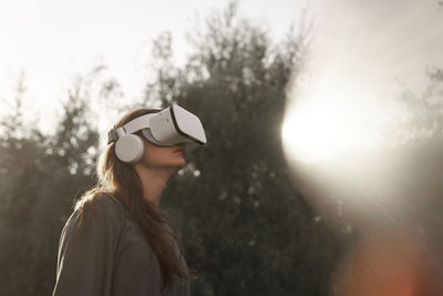 Side view of young woman standing against sky