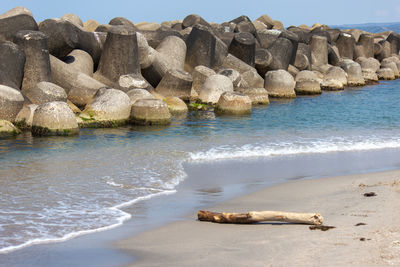 Rocks on beach by sea against sky