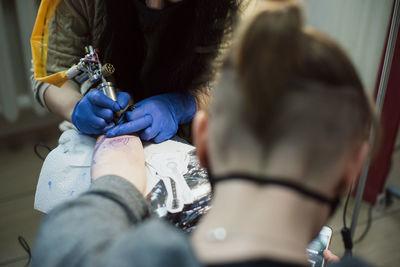 Artist tattooing on hand at studio