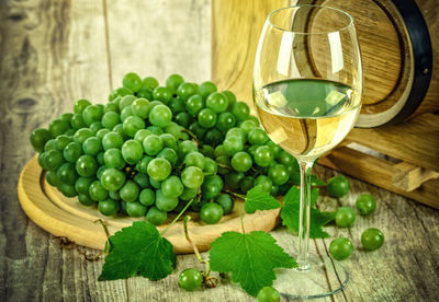 Close-up of grapes by wineglass on table