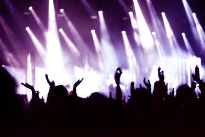 Rear view of silhouette of crowd with arms outstretched at concert. summer music festival concept