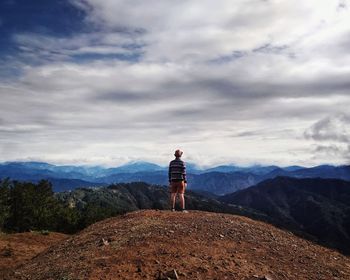 Rear view of man standing on mountain against sky