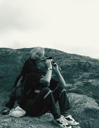 Man photographing on mountain against clear sky