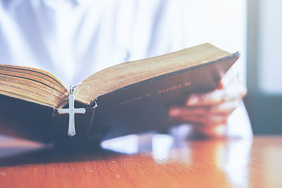 Cropped image of priest reading bible at table