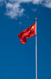 Low angle view of chinese flag waving against blue sky