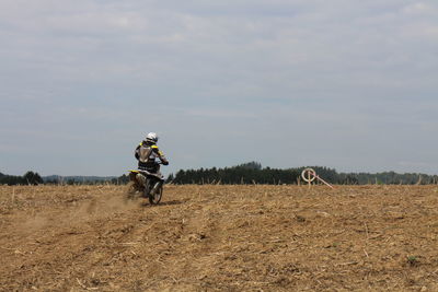 Man riding motorcycle on field against sky