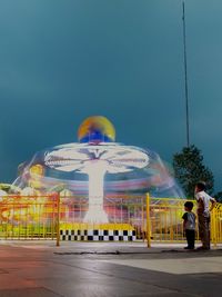 Rear view of man at amusement park against sky