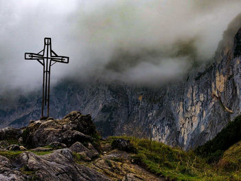 View of cross on rock against sky