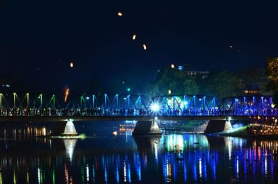 Illuminated boats in city against sky at night