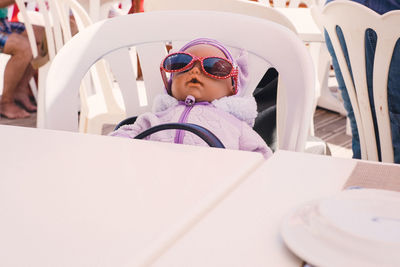 Cute baby girl in sunglasses relaxing on chair