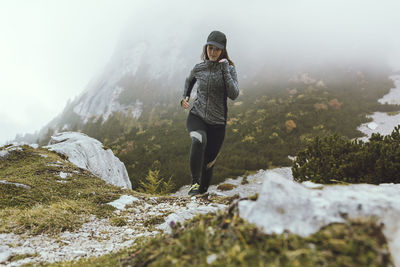 Young woman running on field during foggy weather