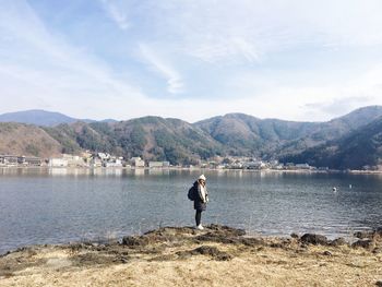 Man standing in lake against mountains