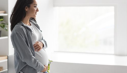 Side view of a woman standing against the wall