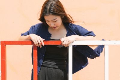 Beautiful young woman standing against wall