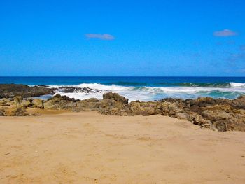 Scenic view of beach against clear blue sky