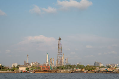 Buildings by river against sky in city