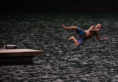 Full length of shirtless man swimming in lake