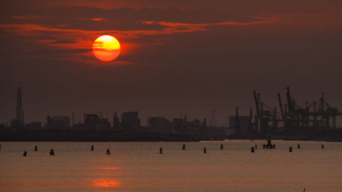 Silhouette of industrial port against sky during sunset