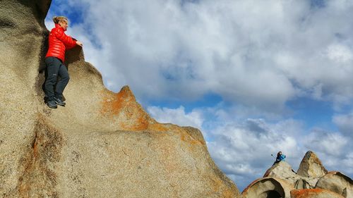 Low angle view of people against cloudy sky