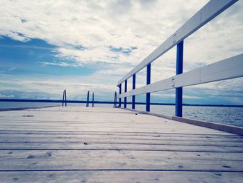 Pier on sea against cloudy sky