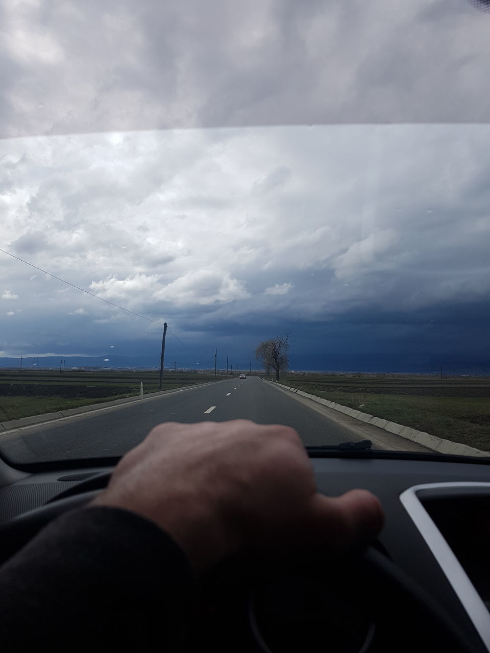 MIDSECTION OF MAN DRIVING CAR AGAINST SKY