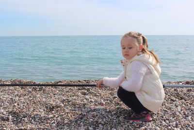 Girl crouching at beach