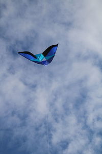 Low angle view of kite flying against cloudy sky