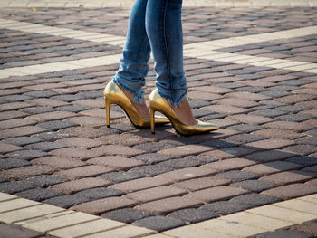 Low section of woman wearing high heels shoe on paved street