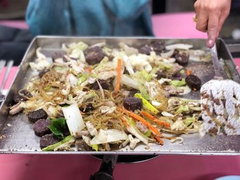 Close-up of vendor preparing food on barbecue grill