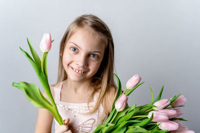 Portrait of smiling girl holding bouquet against white background