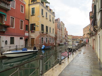 Canal amidst buildings in city against sky